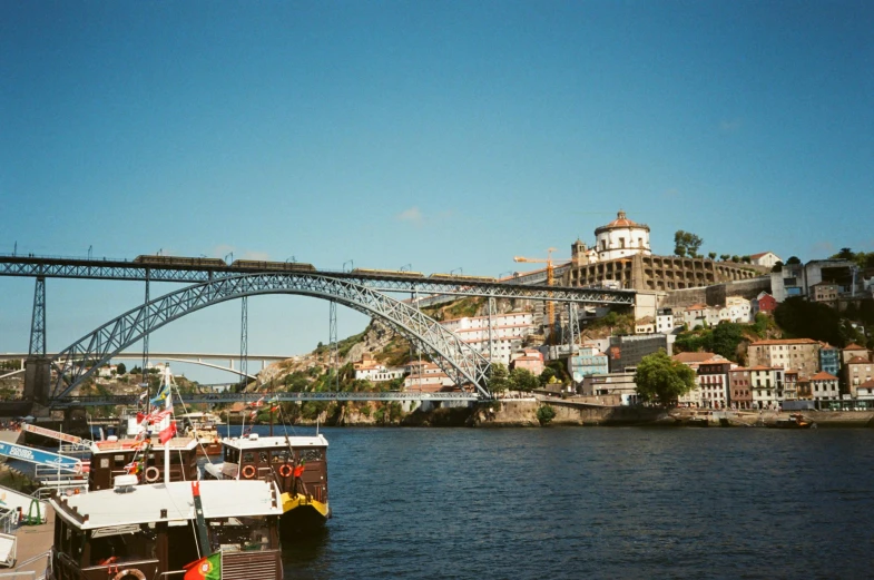 two boats docked on the water with a bridge in the background