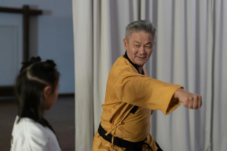 an older man doing karate next to another woman