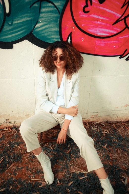 the woman is sitting against a graffiti wall