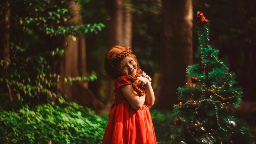 in red dress smiling by tree with decorations