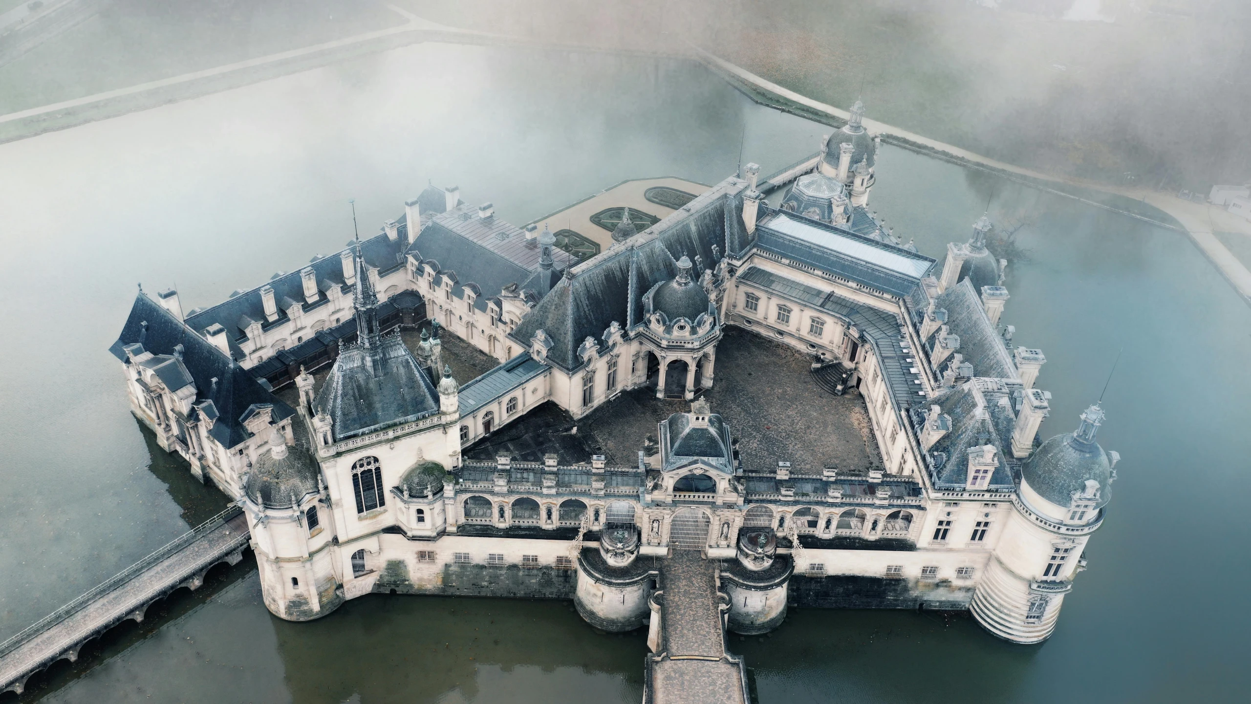 an aerial view of a castle near some water