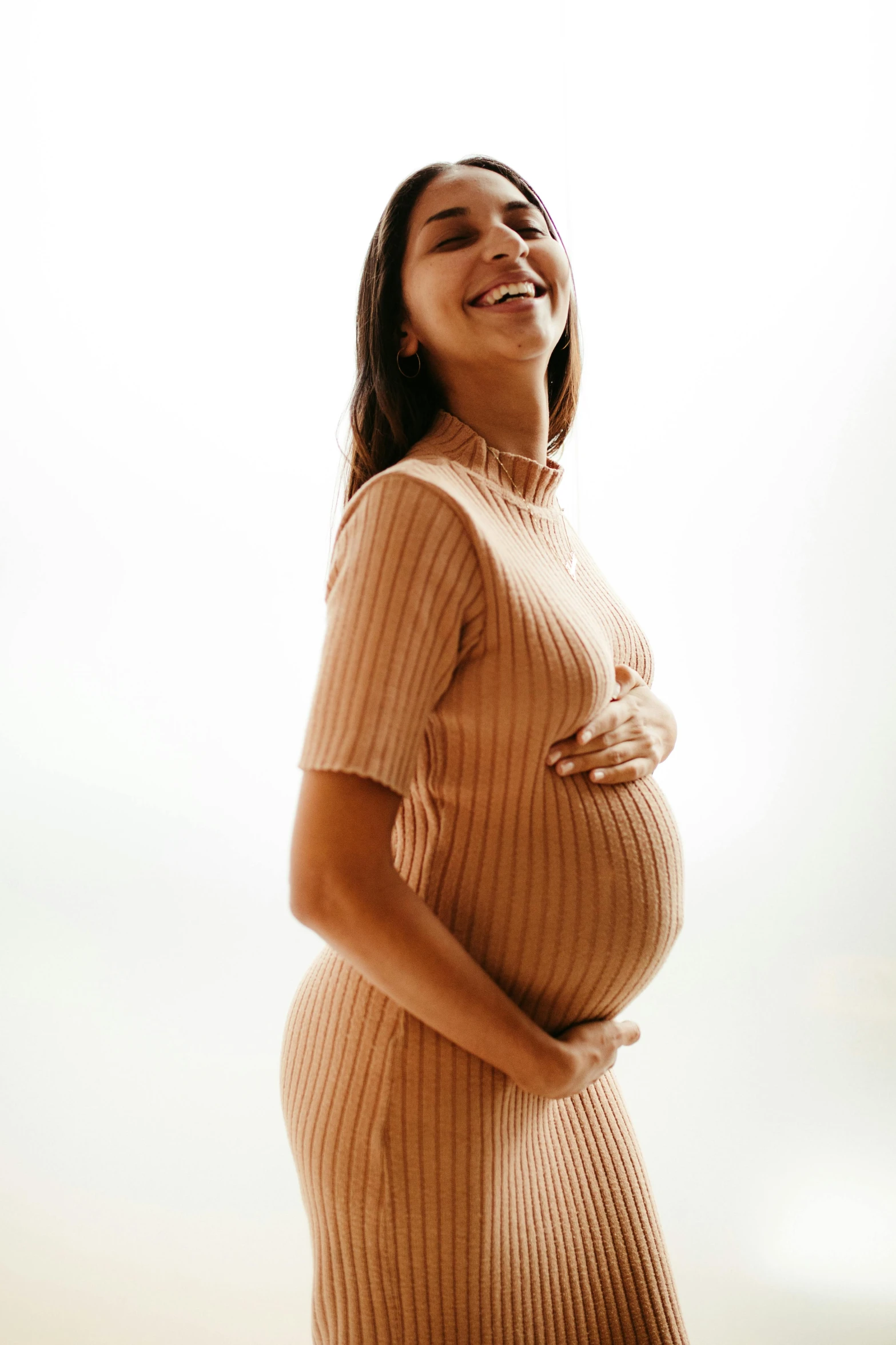 a pregnant woman stands in the sky looking up