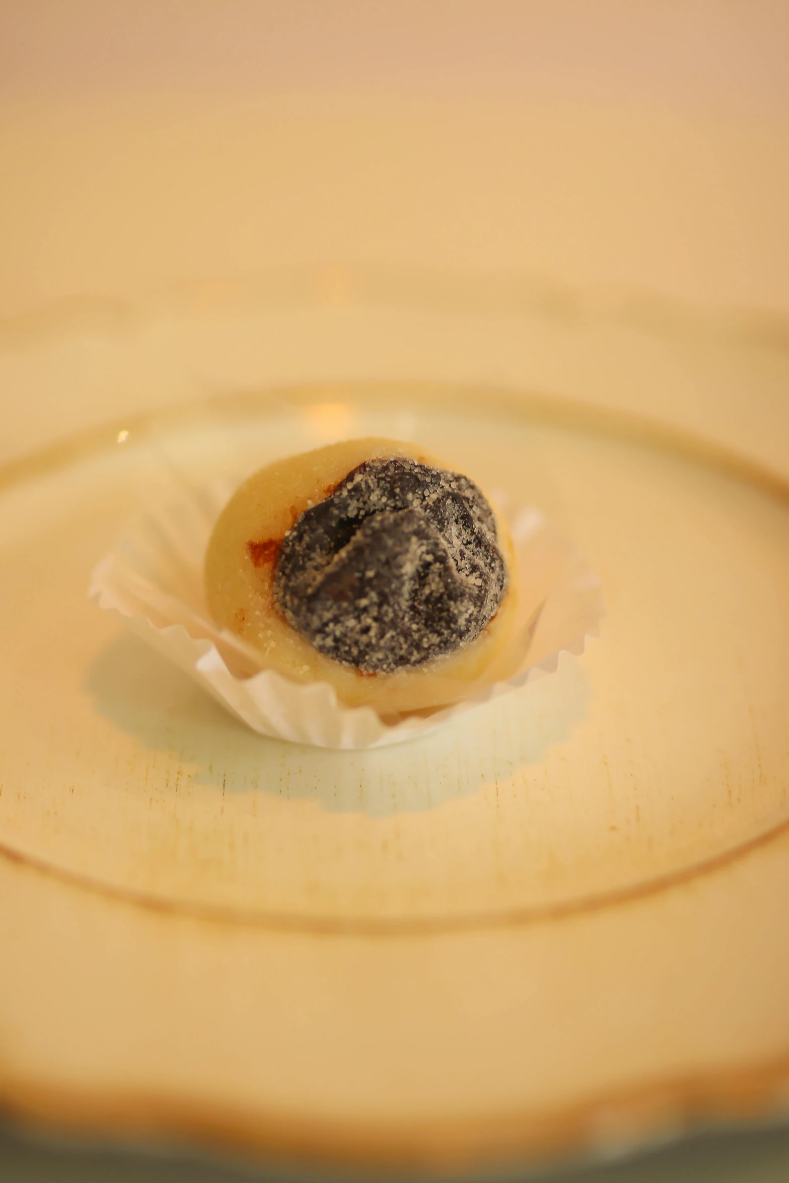 a single doughnut sits on top of paper and on the glass plate