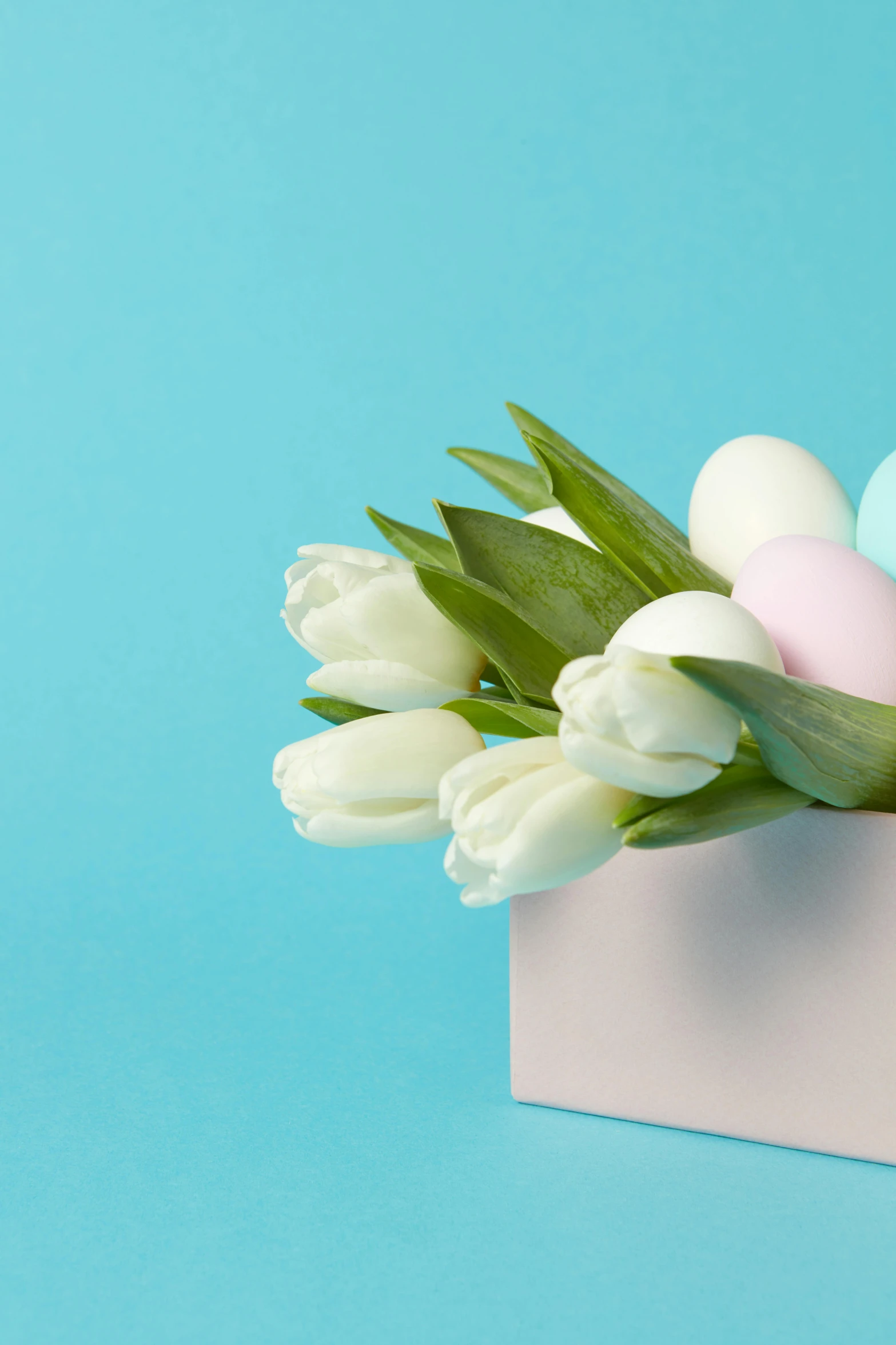 white flowers in vase filled with colored eggs