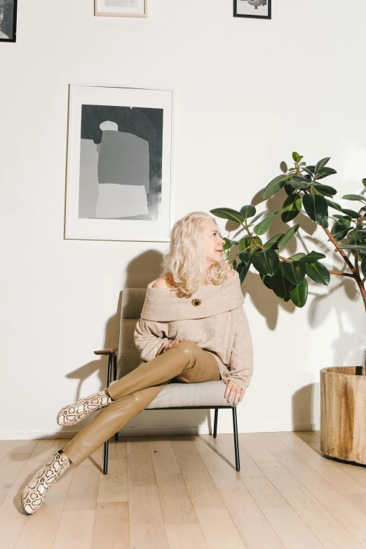 a woman sits on a chair in front of a potted plant