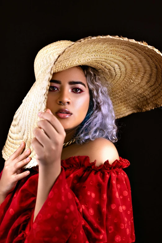 a woman with blue hair wearing a large straw hat