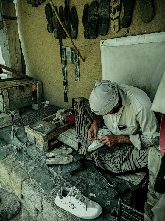 a man sitting down working on a shoe