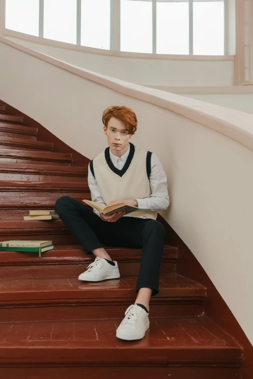 a boy wearing school attire sitting on steps with books