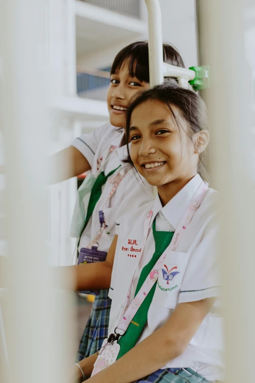 two girls are in white shirts and green ties smiling for the camera