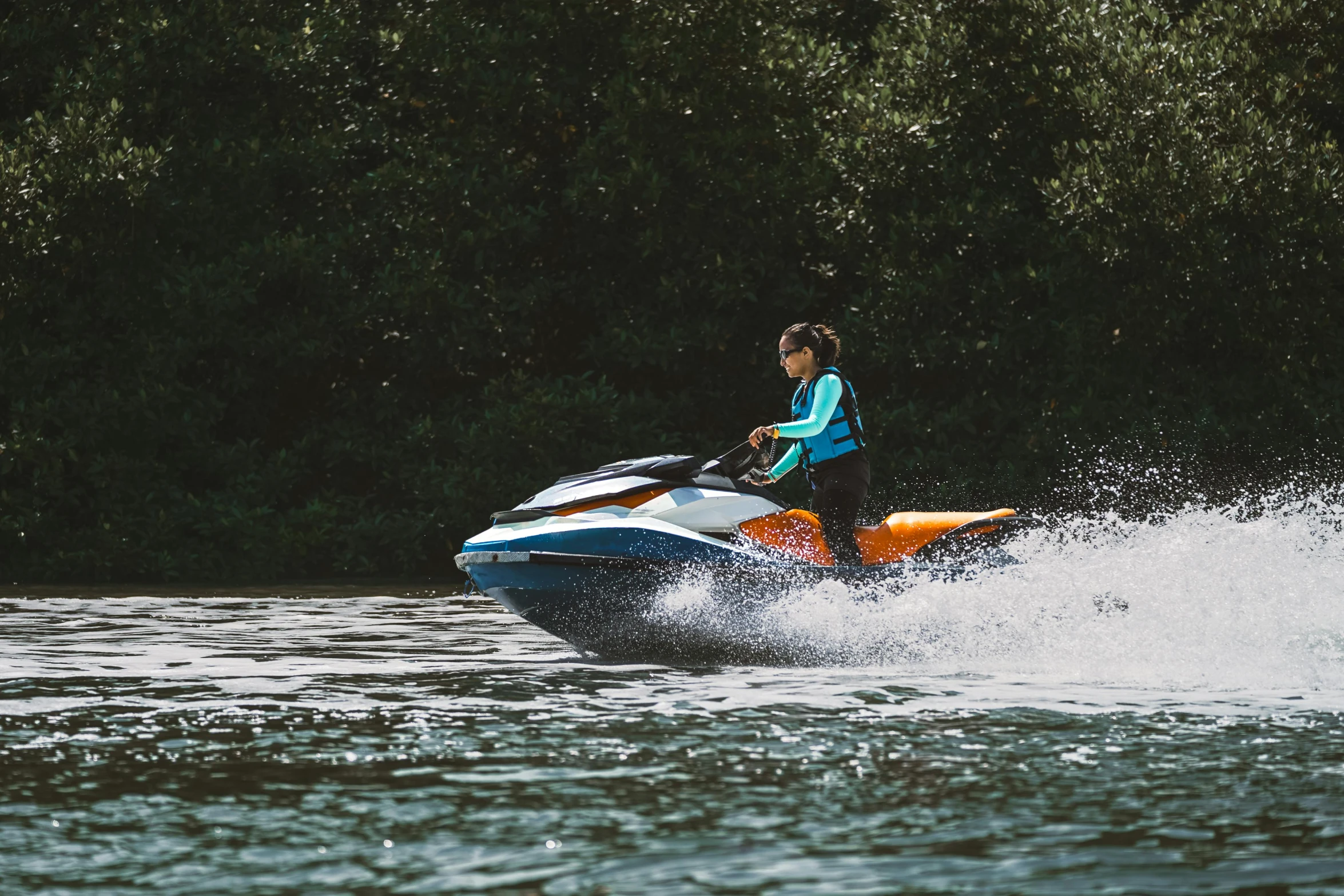 a woman riding on the back of a yellow and white jet ski