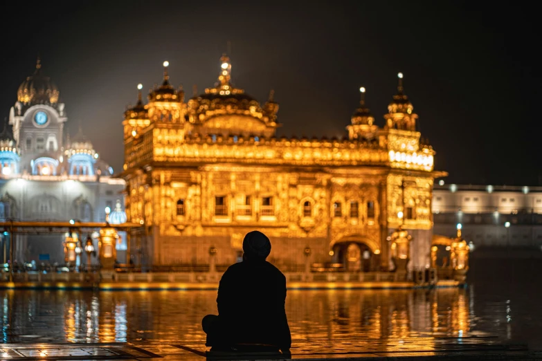 a man sitting by a river in front of a building