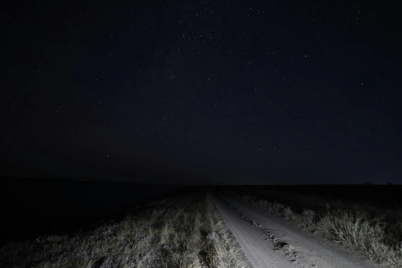 a dark sky night is shown over a road with many stars