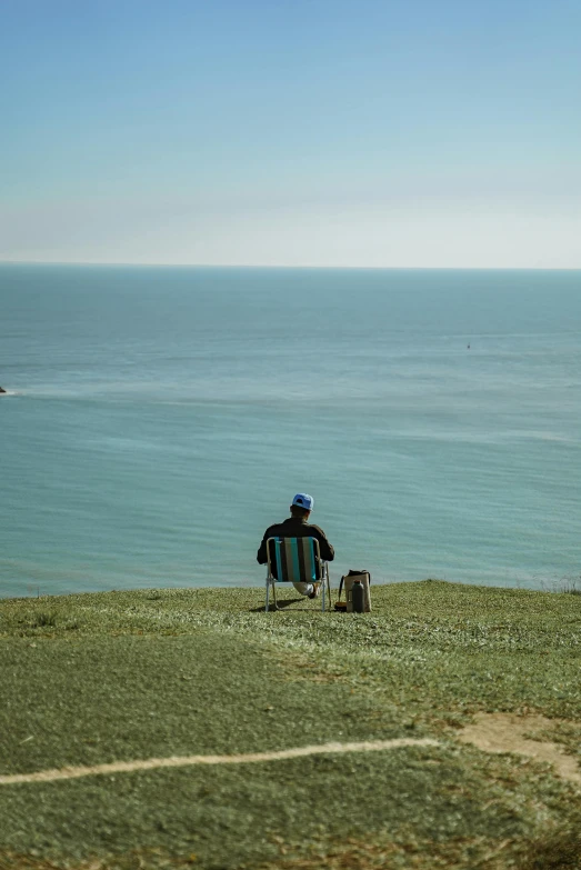 a person sitting on a beach chair by the ocean