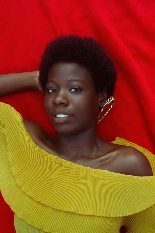 woman in a yellow dress laying on a red background