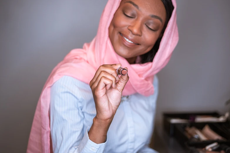 a woman with a light pink scarf and ring