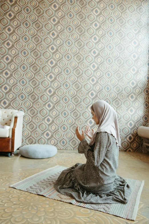 a woman sitting on a rug in front of a wall