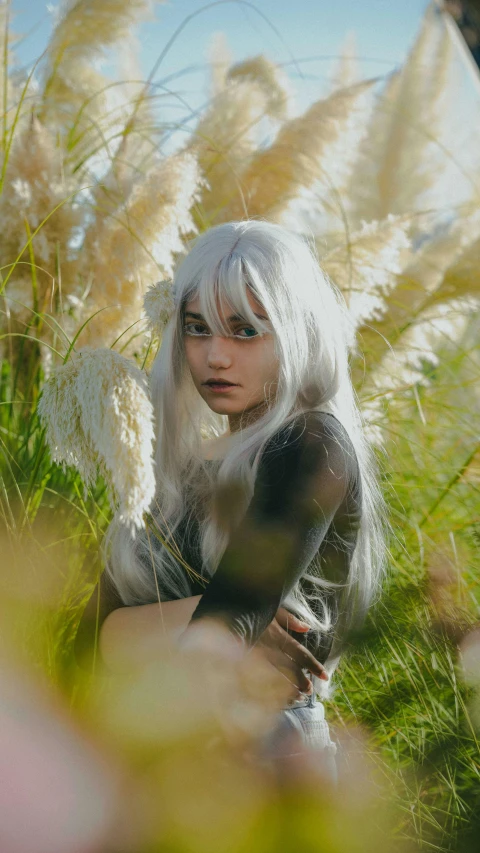 a woman with white hair and makeup sitting on the grass