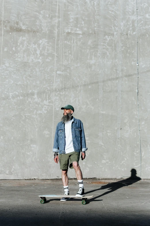 a man in denim shirt and hat riding a skateboard