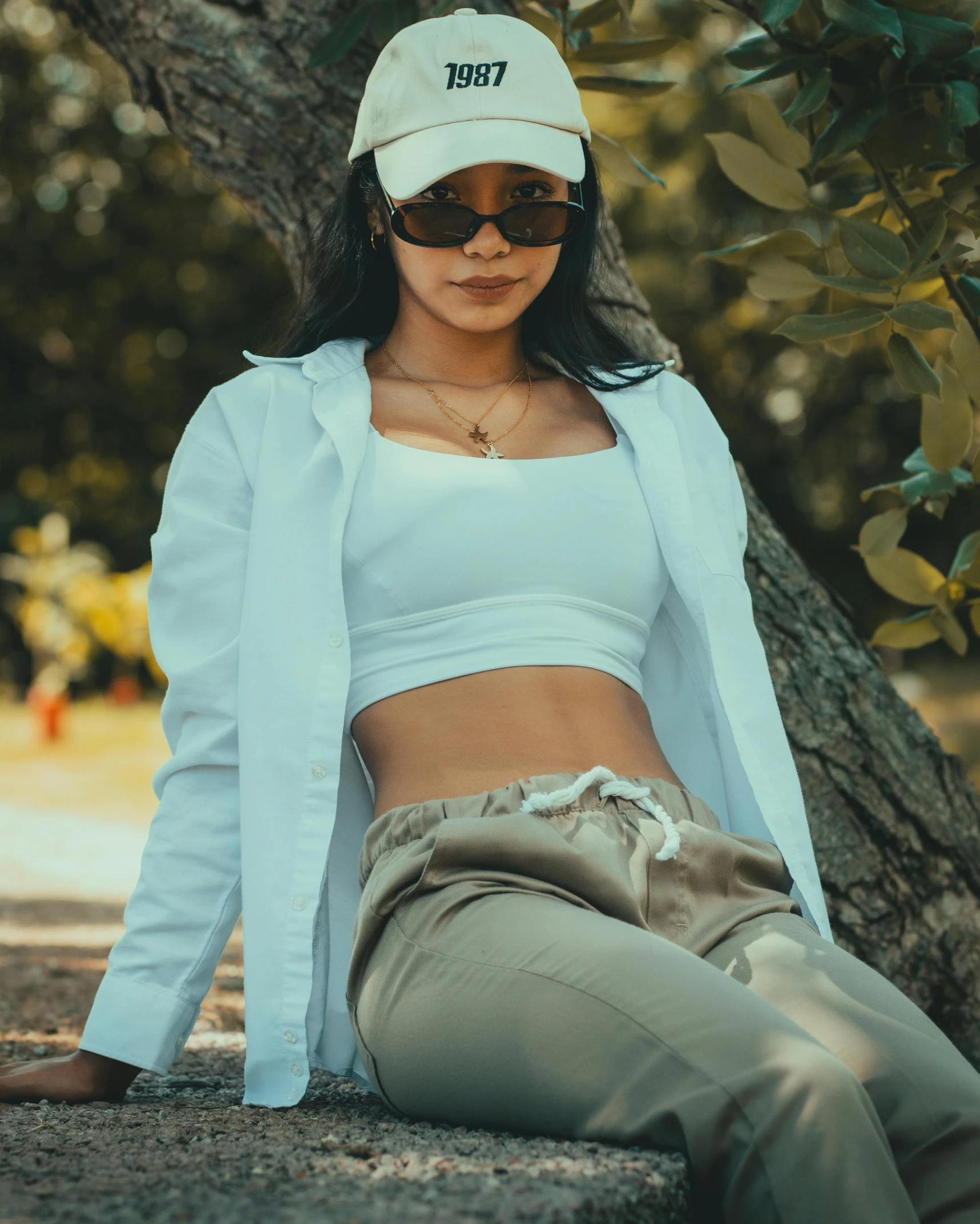 a woman in a hat posing under a tree