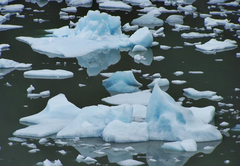 an iceberg with small pieces on top of it floating in the water