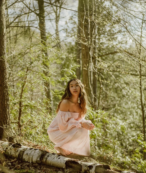 a woman is posing for the camera near some trees