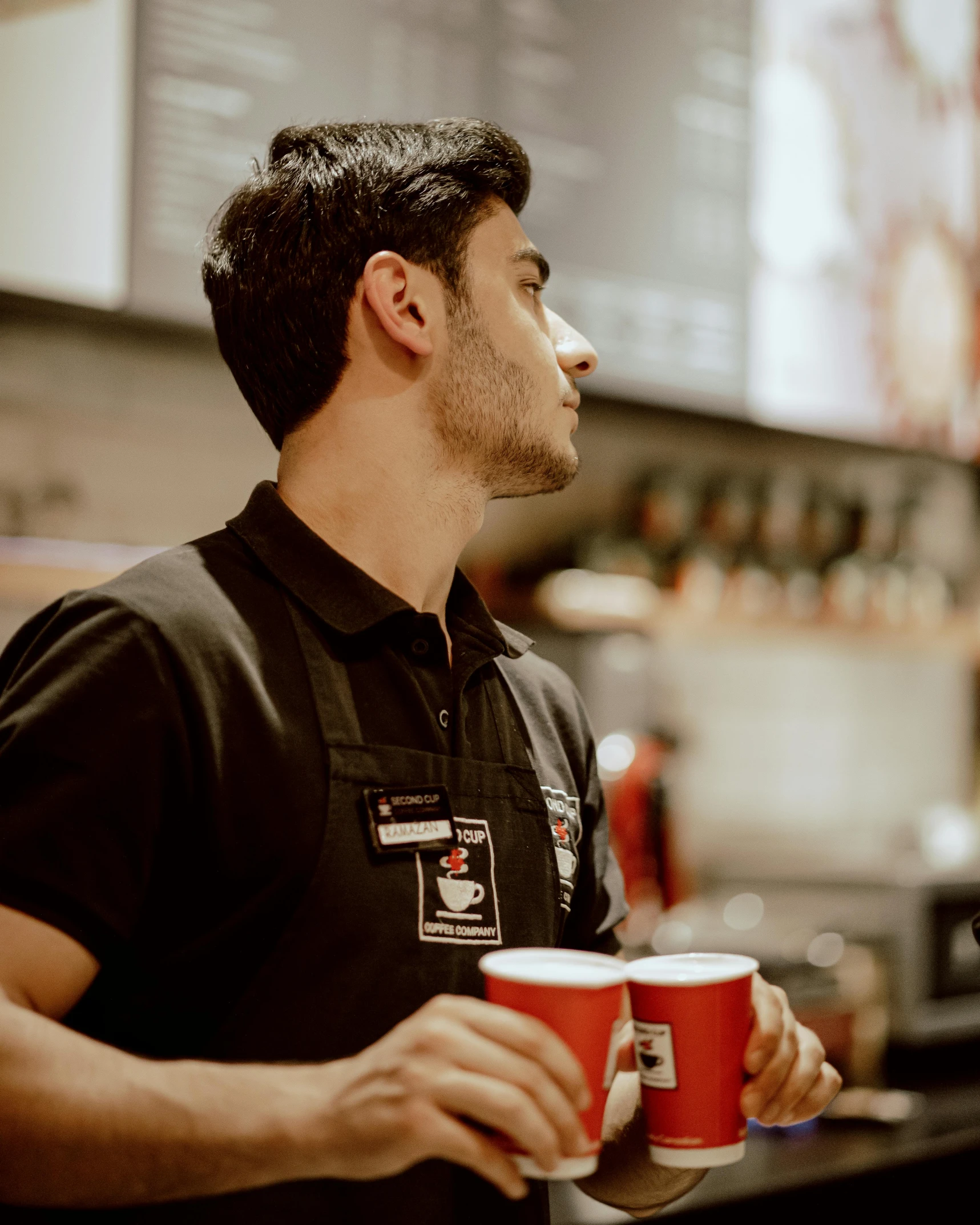 a worker holding two cups of coffee in his hand