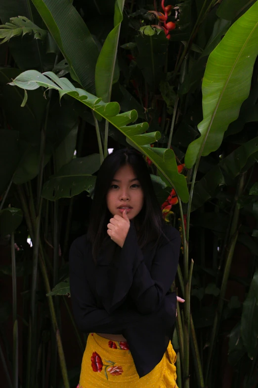 a woman with long hair and in a dress stands among green plants