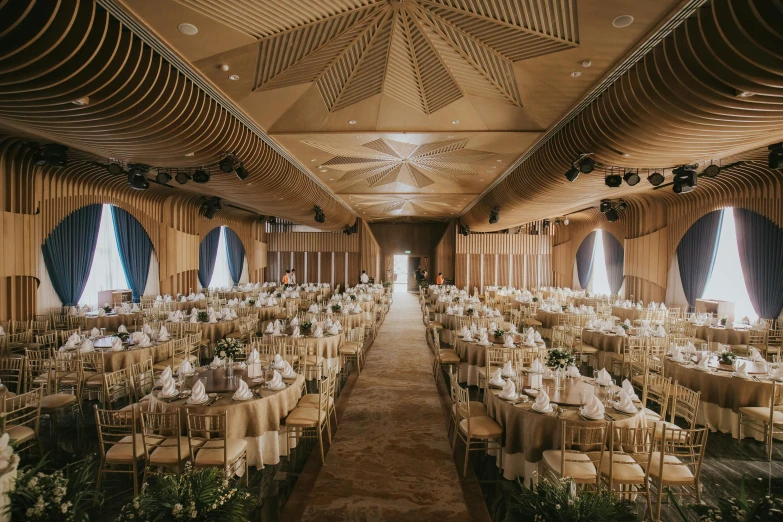 large banquet hall full of white tablecloths and decorated with plants