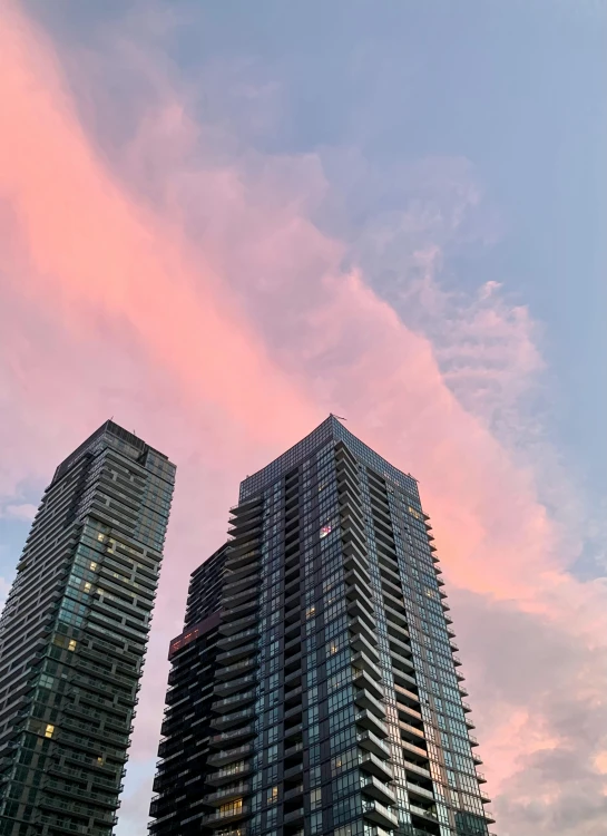 the sky is pink and the buildings are all glass