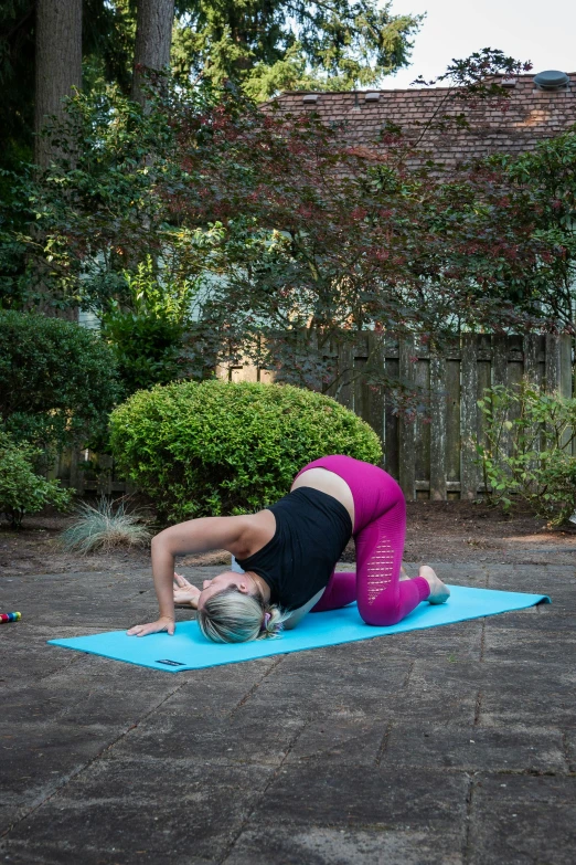 a woman in black shirt doing yoga with a blue mat