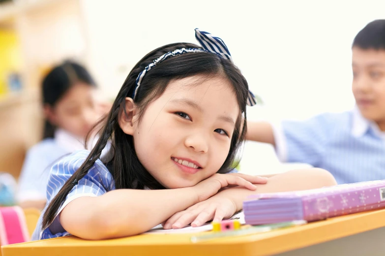 an asian girl at a table smiling and her friends are in the background