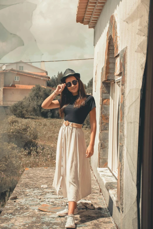 young woman with sunglasses and a hat on walking towards the house