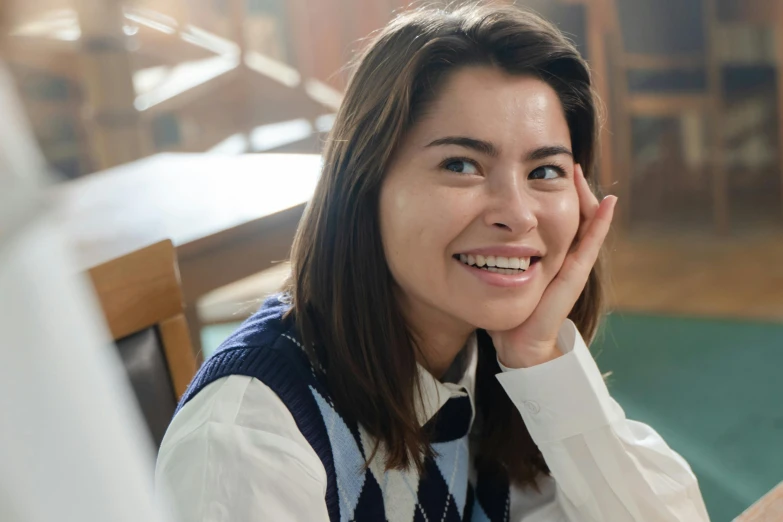 the young woman in striped vest is sitting at table smiling