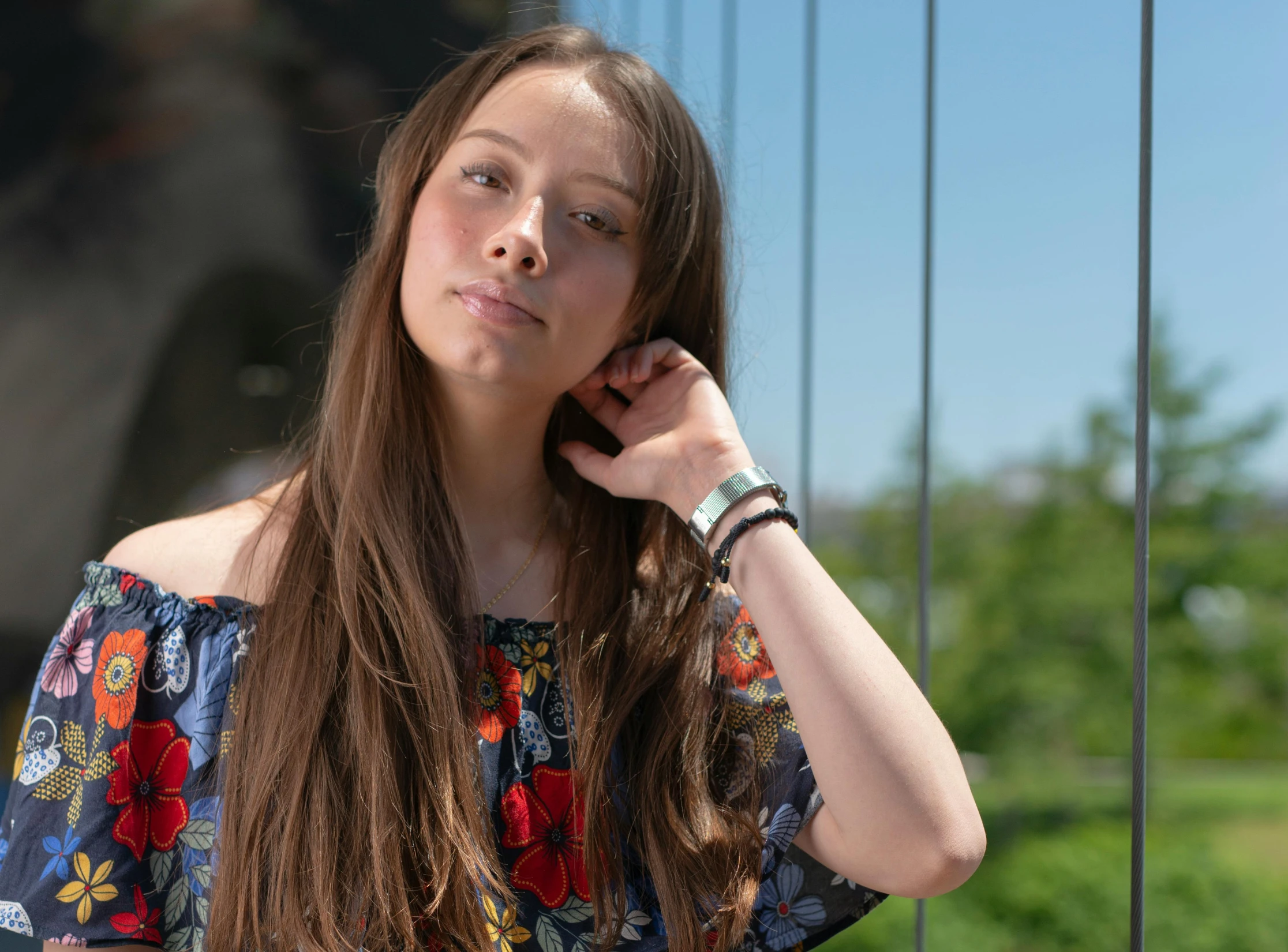 a young woman in a colorful top is leaning against a wire fence