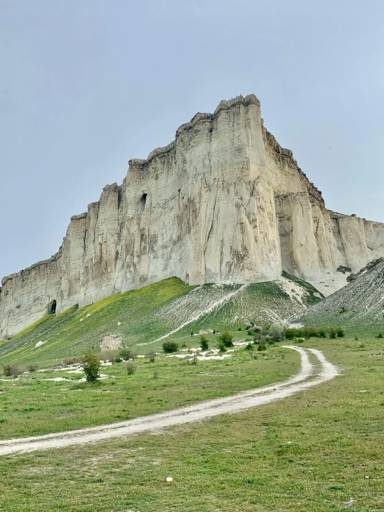 the view of an old hill, with a rock outcropping and a dirt road leading to it