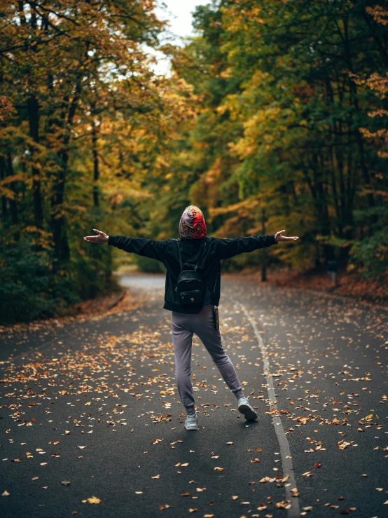 a person standing on the middle of a road in the middle of autumn