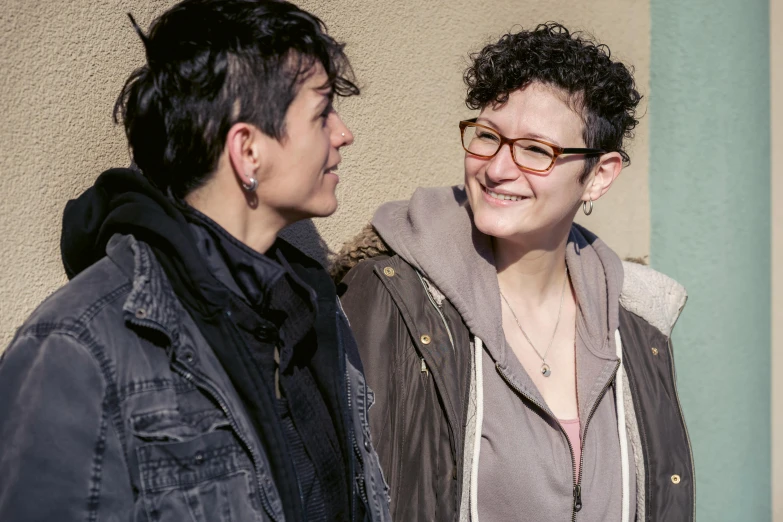 two people smiling together next to a building