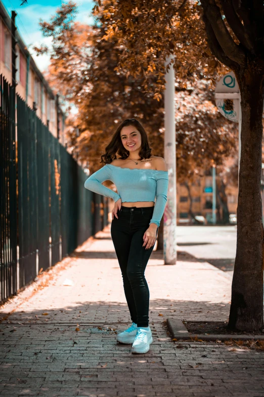 a woman is leaning on a fence by a tree