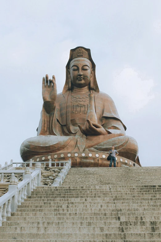 a man standing on a set of steps in front of a giant buddha statue