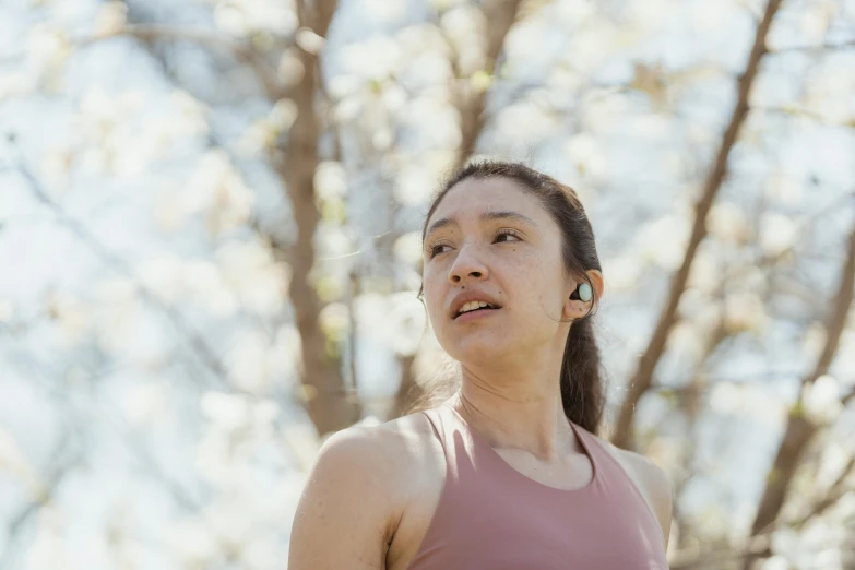 a woman wearing ear buds looking away from the sky