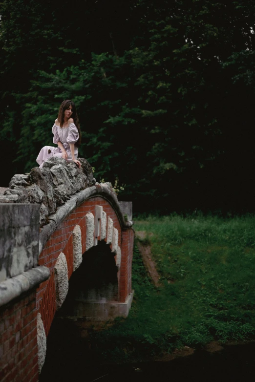 two woman sit on top of a brick bridge