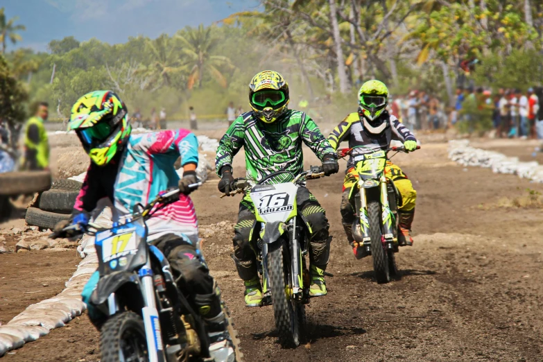 three motorcyclists are going on a dirt track