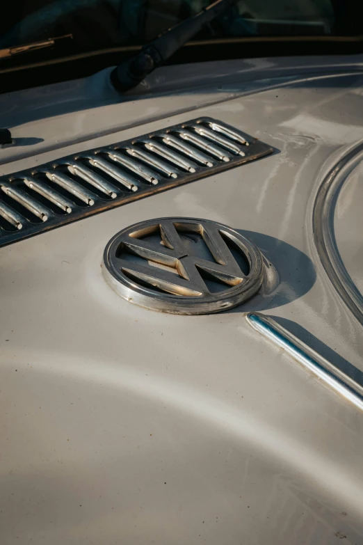 the emblem on a silver vintage car is round