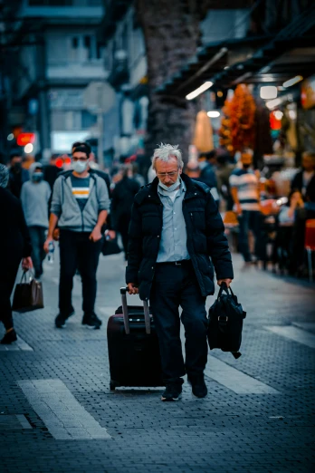 a man with his luggage walks down the sidewalk