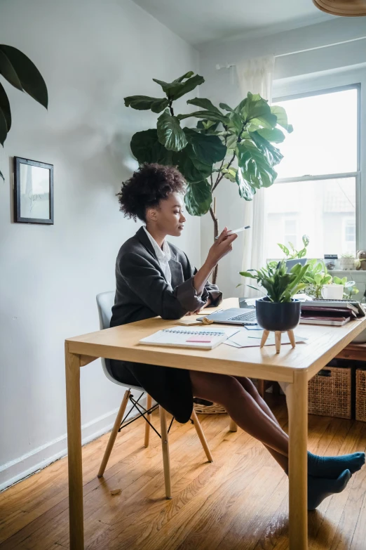 a woman sits at a table with two plants