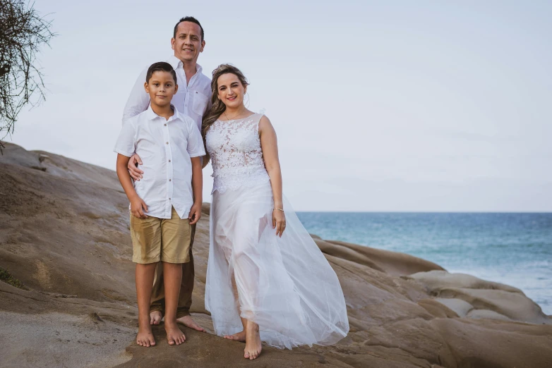 an image of two boys standing with a woman at the beach