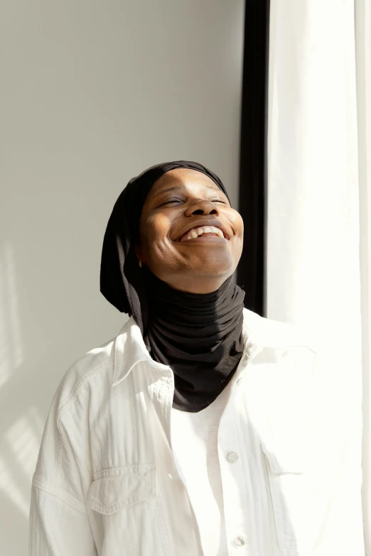 a woman smiles with a neck scarf wrapped around her