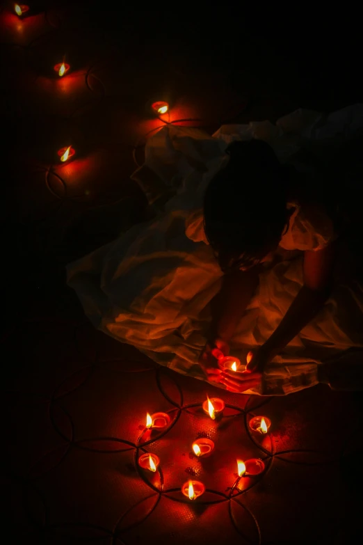 a woman sitting in front of some light up candles