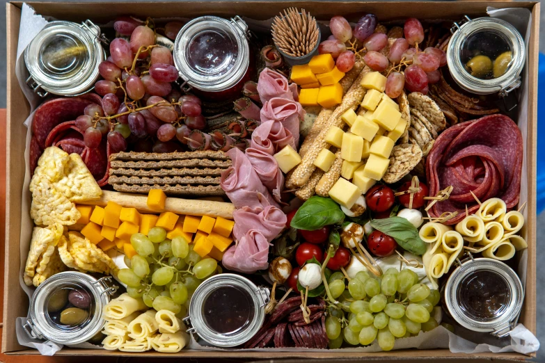 a square box full of cheese, bread and snacks