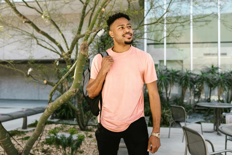 an african american man holding a backpack in a courtyard